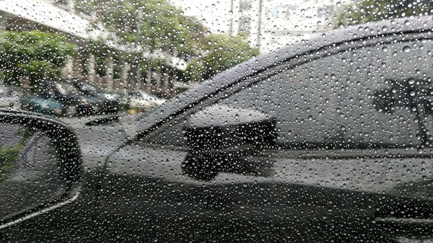 Rain drops on window with car background