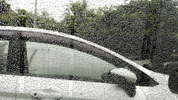 車の背景を持つウィンドウに雨の滴