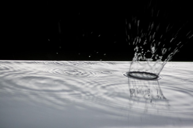 사진 잔물결을 형성하는 물웅덩이에 떨어지는 비와 액체 폭발을 일으키는 물 한 방울이 튀는 거시적 전망