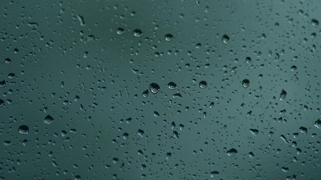 Rain falls on clear glass streams of raindrops on window glass close up