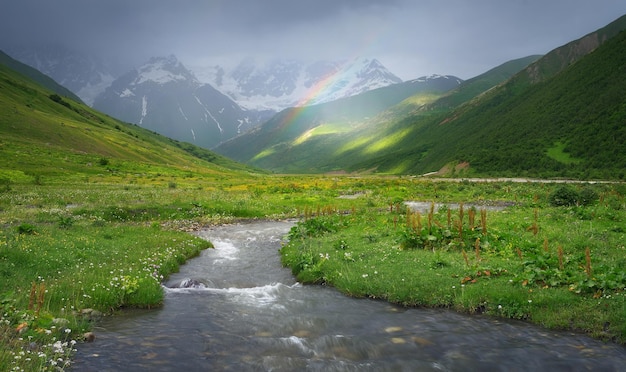 Rain in the mountains. Rainbow over the river. Mountain landscape on a rainy summer day. Caucasus, Georgia, Svaneti. View at the foot of the mountain Shkhara