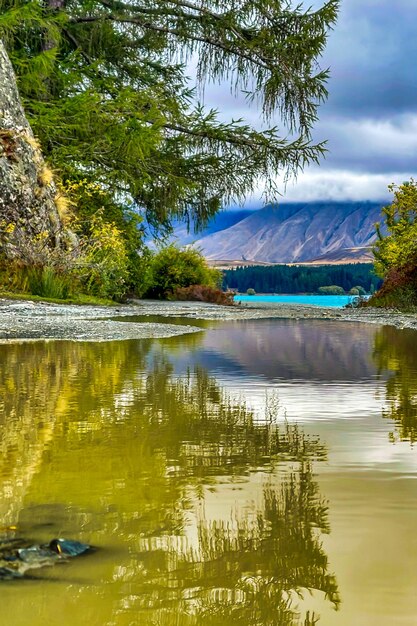 A rain puddle with a lake and mountain range in the background