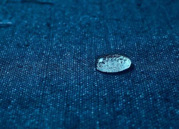 Rain water droplets on blue waterproof fabric.