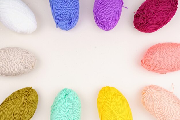 Photo rainbow balls of yarn is beige, yellow, burgundy, light pink, green, blue and white.