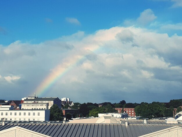 Rainbow over buildings in city against sky