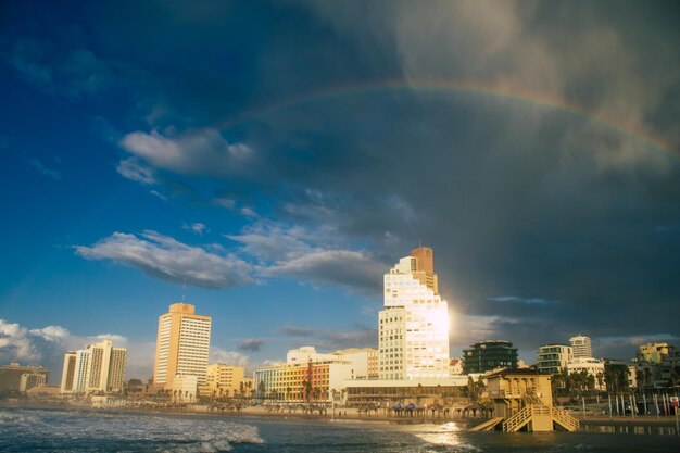 Rainbow over buildings in city against sky