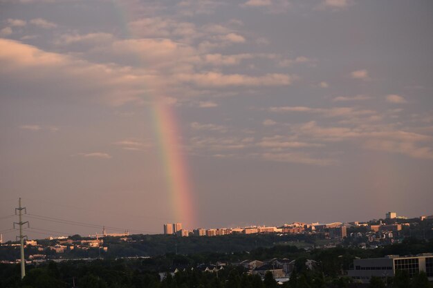 rainbow over city buildings against sky during sunset