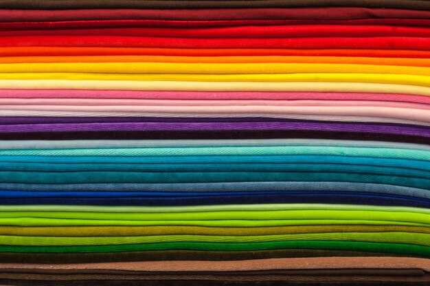 Rainbow clothes background pile of bright folded clothes