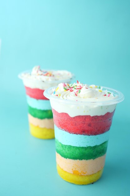 Rainbow color cake in a plastic container on table