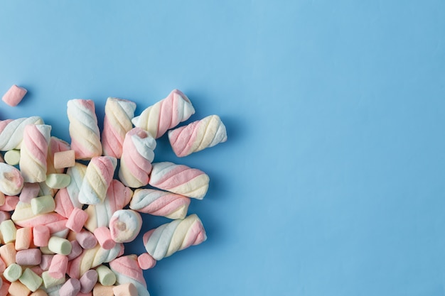 Rainbow color of spiral marshmallows on blue background