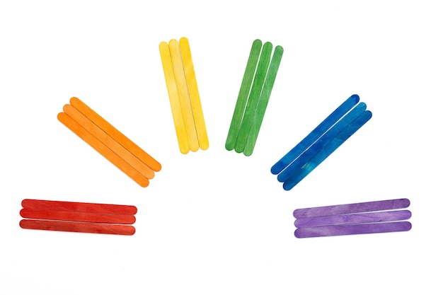 Photo rainbow color wooden ice cream sticks on white. colorful abstract arch, lgbt concept.