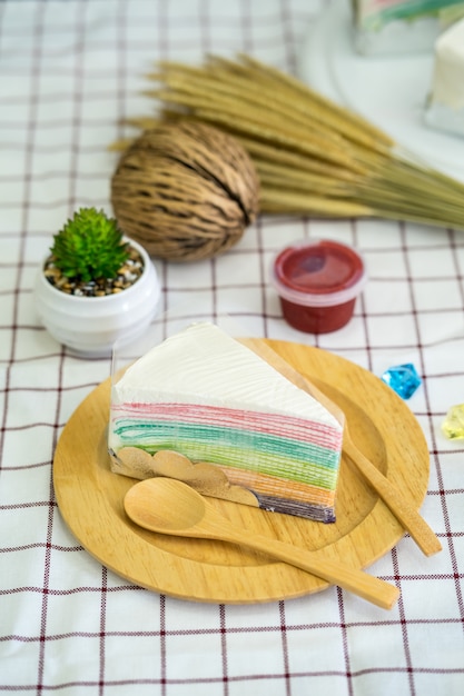 Rainbow crepe cake with strawberry jam on wooden plate 