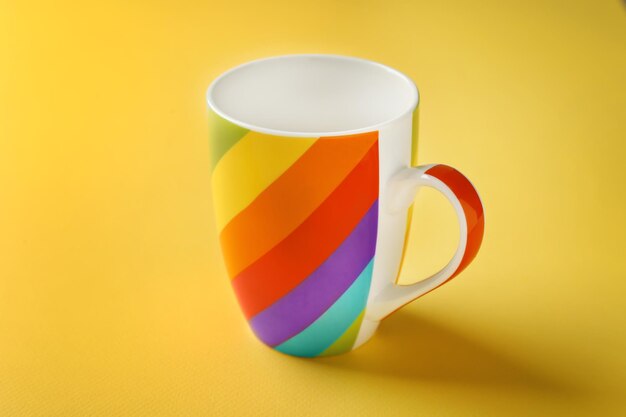 Rainbow cup on color background