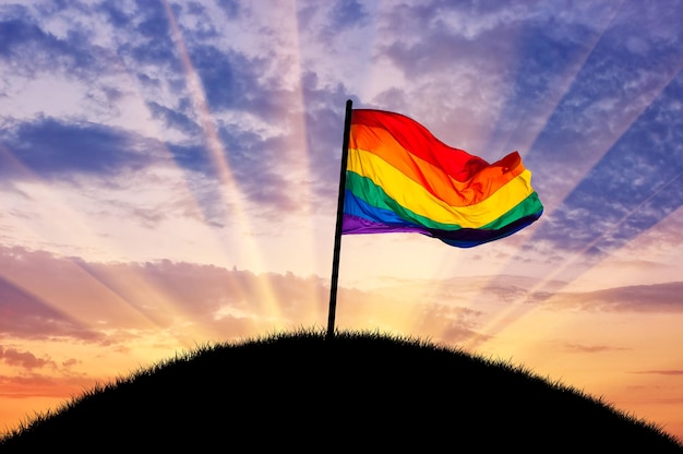 Rainbow flag on a hilltop at sunset