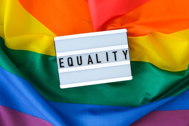 Foto bandiera arcobaleno con scatola luminosa e testo di uguaglianza bandiera arcobaleno lgbtq fatta di materiale di seta simbolo