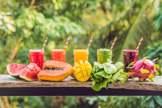 Photo rainbow from smoothies. watermelon, papaya, mango, spinach and dragon fruit. smoothies, juices, beverages, drinks variety with fresh fruits on a wooden table