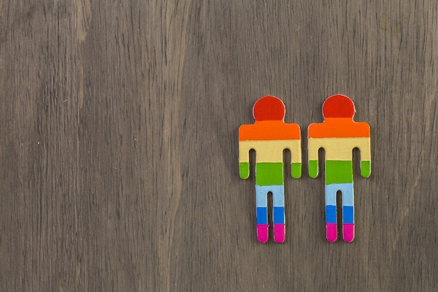 Rainbow Gay Pride male and female figures on wood background.