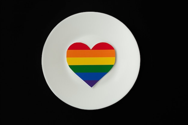 Photo rainbow heart on a white plate, a black surface