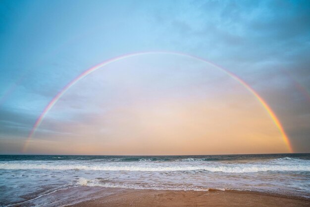 a rainbow is in the sky above the ocean