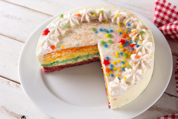 Rainbow layer cake piece on wooden table