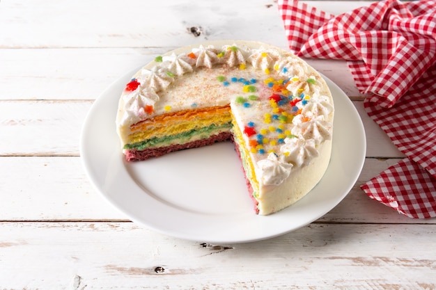 Rainbow layer cake on white wooden table