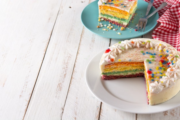 Rainbow layer cake on white wooden table