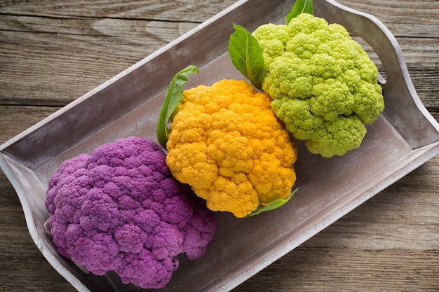 Rainbow of organic cauliflower on the wooden table.