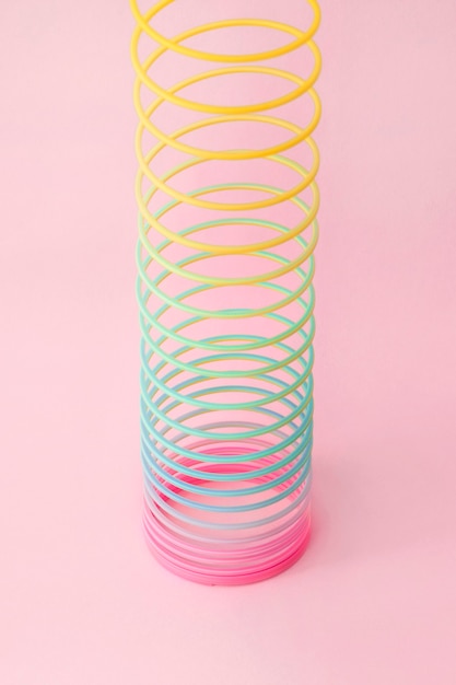 Rainbow plastic spring toy on pink background