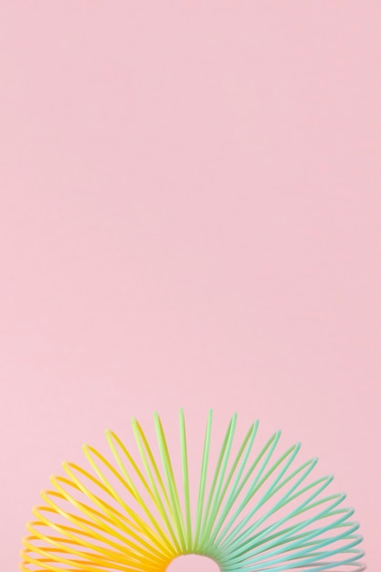 Rainbow plastic spring toy on pink background