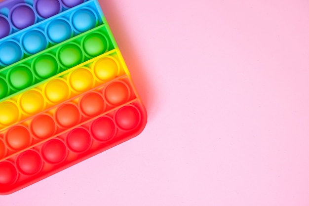 Rainbow pop it toy fidget on a background of empty copy space. pink background