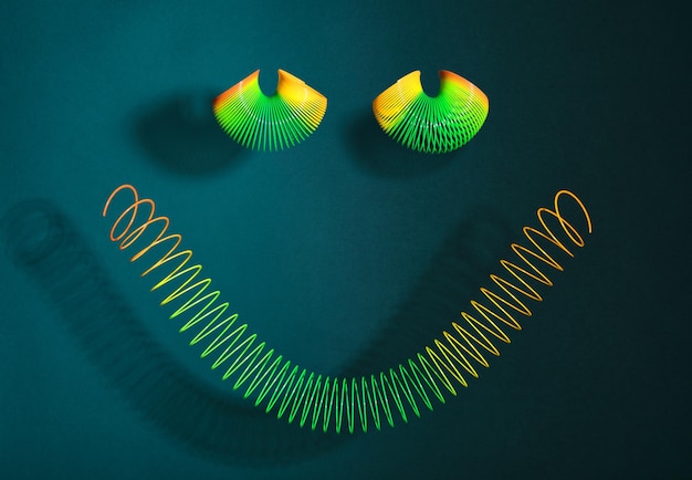 Rainbow spiral toys in form happy smiley on green background Idea positive mood