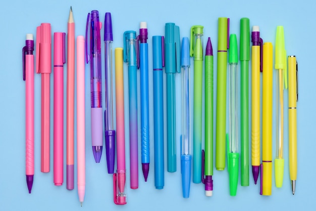 Rainbow stationery collection of pens and pencils on a light blue background