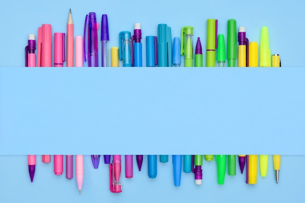 Rainbow stationery collection of pens and pencils on a light blue background