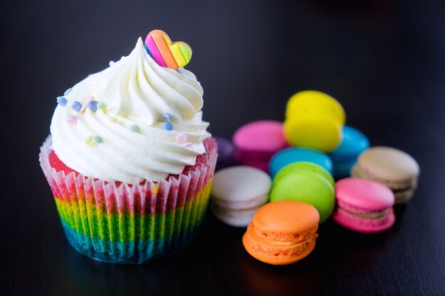 rainbow topped cupcake with colorful macarons