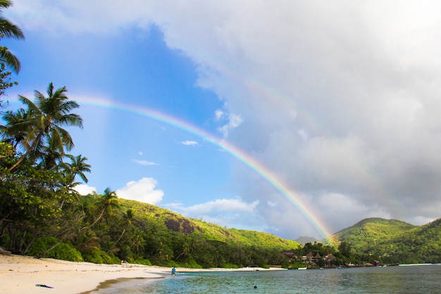 Rainbow over tropical island and white beach at Seychelles