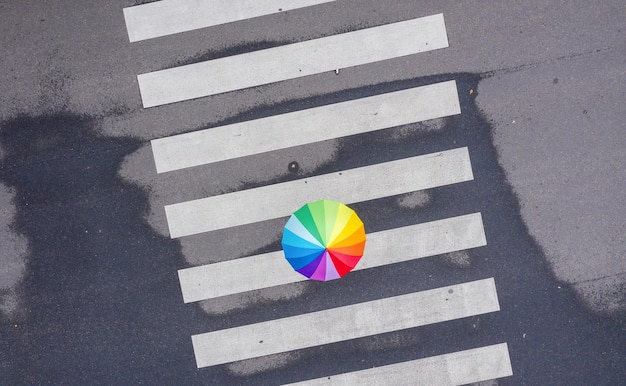 rainbow umbrella on a pedestrian crosswalk - view from a drone