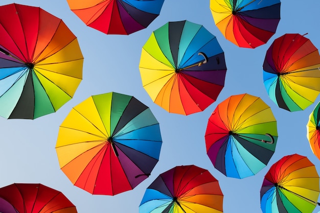 Rainbow umbrellas on a blue sky background