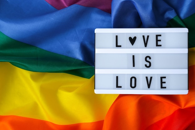 Rainbow vlag met lightbox en tekst liefde is liefde regenboog lgbtq vlag gemaakt van zijde materiaal symbool