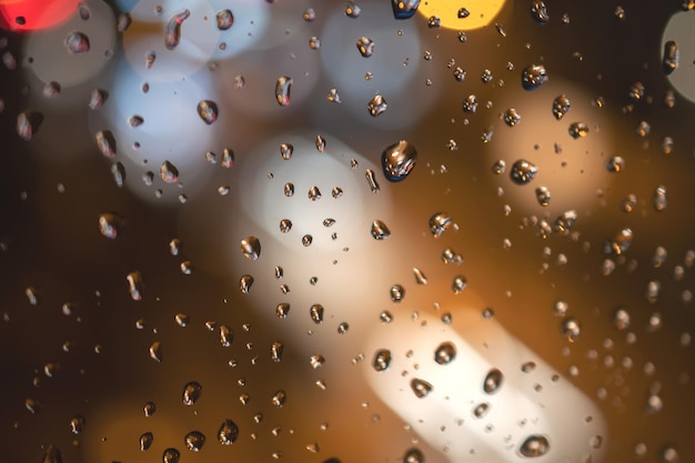 青いガラスの背景に雨滴通りのボケ味の焦点が合っていない抽象的な背景