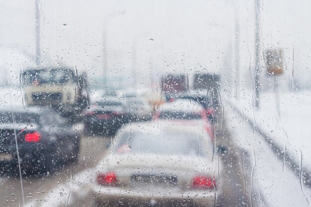 交通の景色を望む車のガラスの雨滴