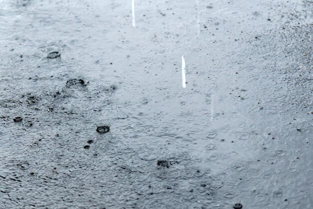 Photo raindrops falling on the water in a puddle on the street selective focus