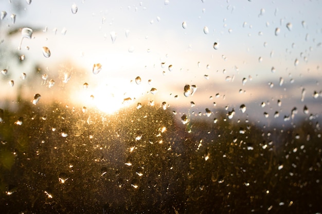 夕日を背景にしたガラスの雨滴