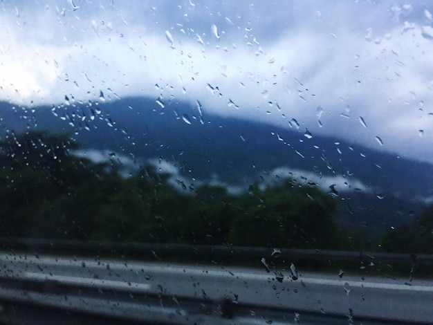 写真 雨季の空に照らされたガラスの窓の上の雨滴