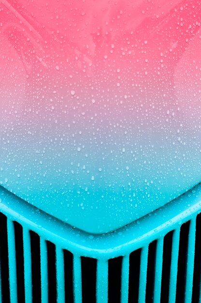 Капли дождя на розовой до бирюзовой решетке автомобиля