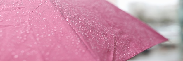 Raindrops running down wet pink umbrella closeup repair of umbrellas and accessories concept