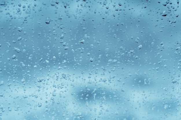 Raindrops on window glass, toned blue