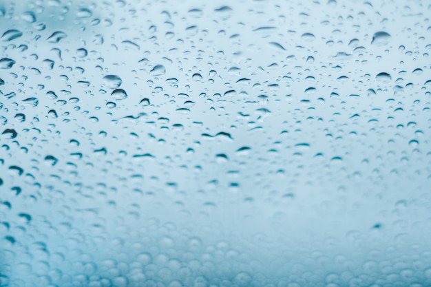 Raindrops on the window. Water droplets on glass. Blue tone