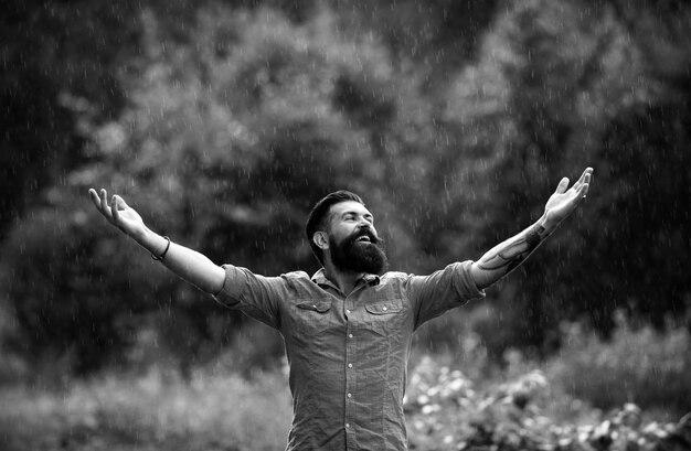 Photo raining man under summer rain portrait of happy bearded man carefree on nature adult optimism and alone time