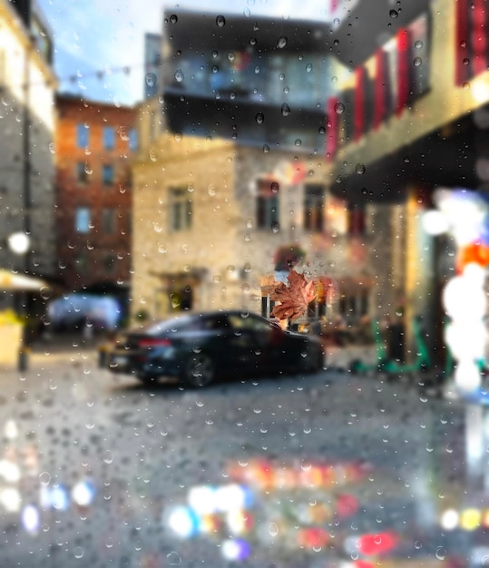 Rainy city modern buildings and gar on street blurred\
light