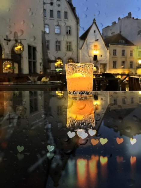 rainy evening city light   and  glass  cup with  candle on  cafe table on street